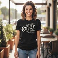 Load image into Gallery viewer, Woman wearing a black t-shirt with a coffee-themed design in an outdoor setting.