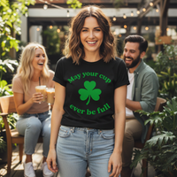 Load image into Gallery viewer, Woman wearing a black t-shirt with a green shamrock design and text, standing outdoors with friends in the background.