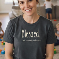 Load image into Gallery viewer, Woman wearing a t-shirt with 'Blessed...and extremely caffeinated.' text in a casual indoor setting.