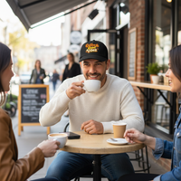 Load image into Gallery viewer, Man drinking coffee with two women at an outdoor cafe