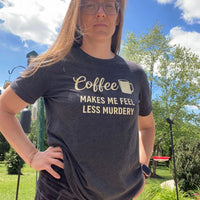 Load image into Gallery viewer, Woman wearing Coffee Makes Me Feel Less Murdery t-shirt in dark grey heather, outdoor backyard