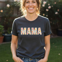 Load image into Gallery viewer, Woman wearing a dark blue t-shirt with 'MAMA' printed in colorful letters outdoors.
