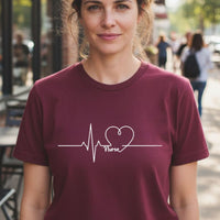 Load image into Gallery viewer, Pulse of Everyday Care nurse tee in maroon on woman outside, white heartbeat and Nurse design, funny nurse t-shirt