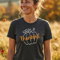 Load image into Gallery viewer, Thankful Pumpkin Everyday Tee worn by a woman smiling in a golden fall field
